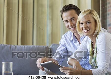 Couple using tablet computer on sofa View Large Photo Image Stock Photo - Couple using tablet computer on sofa. Fotosearch
