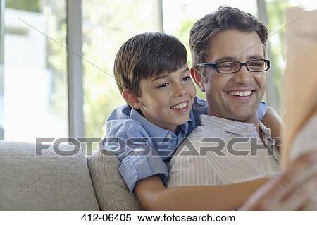 Stock Photography - Father and son hugging on sofa. Fotosearch