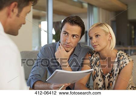 Stock Image - Financial advisor talking to couple on sofa. Fotosearch