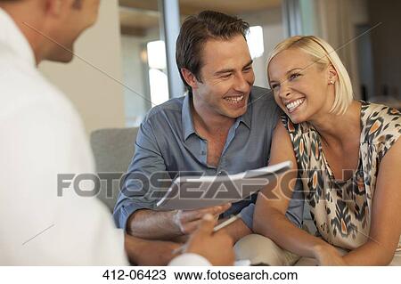 Stock Image - Financial advisor talking to couple on sofa. Fotosearch