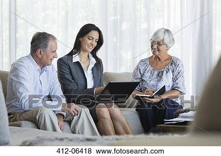 Stock Photo - Financial advisor talking to couple on sofa. Fotosearch