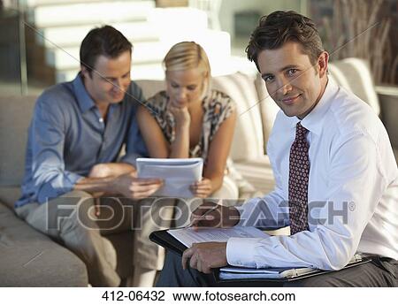 Stock Image - Financial advisor with couple on sofa. Fotosearch