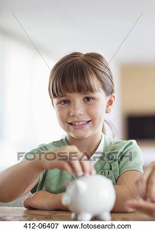 Girl filling piggy bank on counter View Large Photo Image Stock Photo - Girl filling piggy bank on counter. Fotosearch