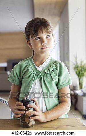 Girl holding change jar at table View Large Photo Image Stock Photography - Girl holding change jar at table. Fotosearch