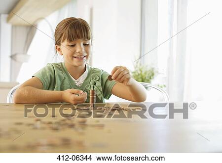 Picture - Girl stacking pennies on counter. Fotosearch