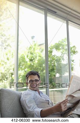 Man reading newspaper on sofa View Large Photo Image Stock Image - Man reading newspaper on sofa. Fotosearch