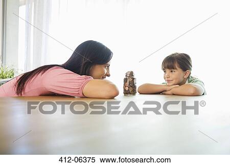 Stock Photography - Mother and daughter with change jar. Fotosearch