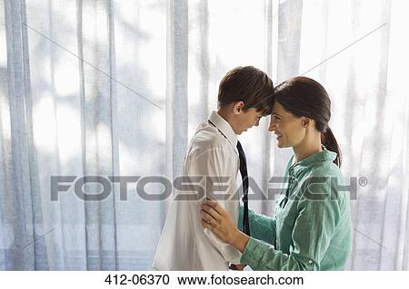 Stock Image - Mother and son touching foreheads at window. Fotosearch