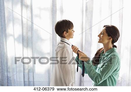 Mother tying son's tie at window View Large Photo Image Stock Photo - Mother tying son's tie at window. Fotosearch
