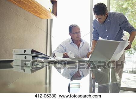 Older and younger man talking at desk View Large Photo Image Stock Image - Older and younger man talking at desk. Fotosearch