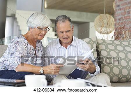 Older couple reading papers together on sofa View Large Photo Image Picture - Older couple reading papers together on sofa. Fotosearch