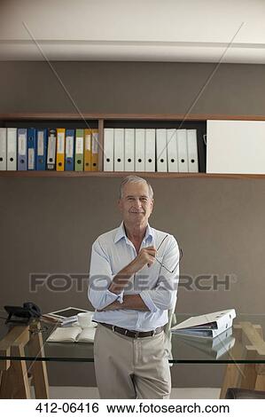 Older man standing in office View Large Photo Image Stock Photograph - Older man standing in office. Fotosearch