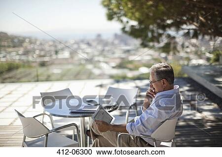 Stock Image - Older man using tablet computer outdoors. Fotosearch