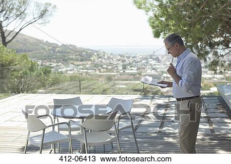 Stock Image - Older man using tablet computer outdoors. Fotosearch