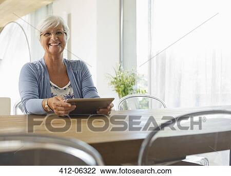 Older woman using tablet computer at table View Large Photo Image Stock Image - Older woman using tablet computer at table. Fotosearch