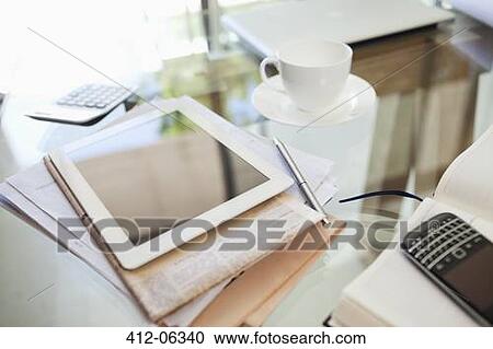 Stock Image - Tablet computer, newspaper, coffee cup and cell phone on desk. Fotosearch