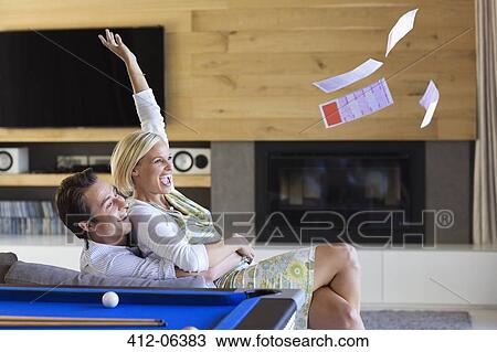 Stock Image - Woman tossing lottery tickets in living room. Fotosearch