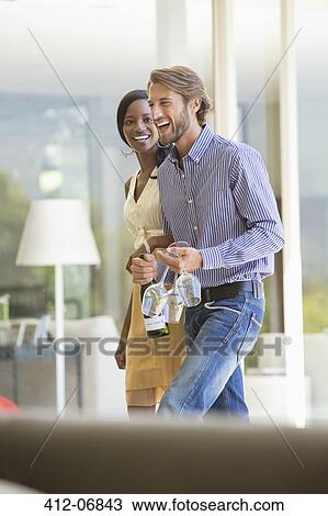 Stock Image - Couple carrying wine bottle and glasses. Fotosearch