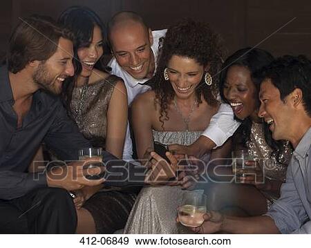 Friends using cell phone at party View Large Photo Image Stock Photo - Friends using cell phone at party. Fotosearch