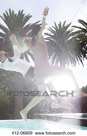 Stock Photo - Fully dressed couple jumping into swimming pool. Fotosearch