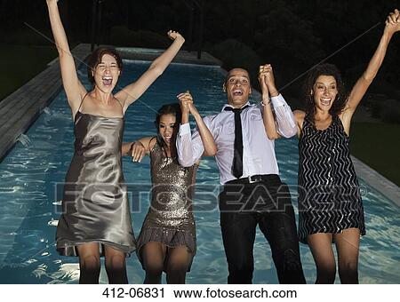 Stock Image - Fully dressed friends jumping into swimming pool. Fotosearch