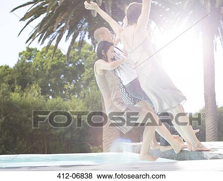 Stock Photo - Fully dressed friends jumping into swimming pool. Fotosearch