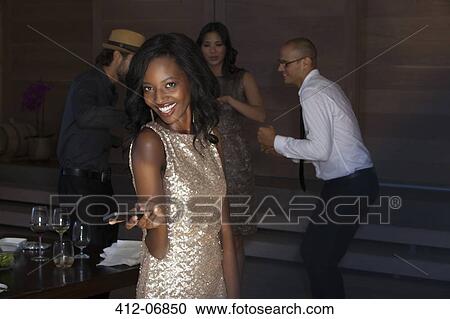 Stock Image - Woman using cell phone at party. Fotosearch