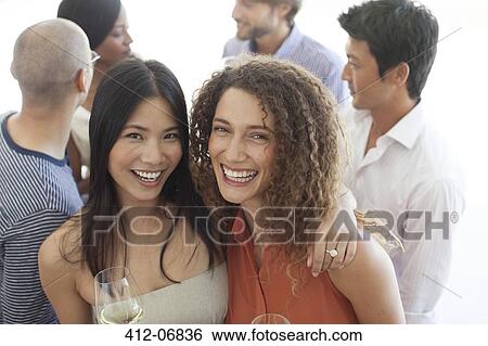 Stock Photograph - Women smiling together at party. Fotosearch