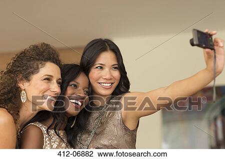Stock Image - Women taking picture together indoors. Fotosearch