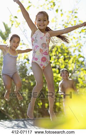 Stock Photo - Children jumping on trampoline outdoors. Fotosearch