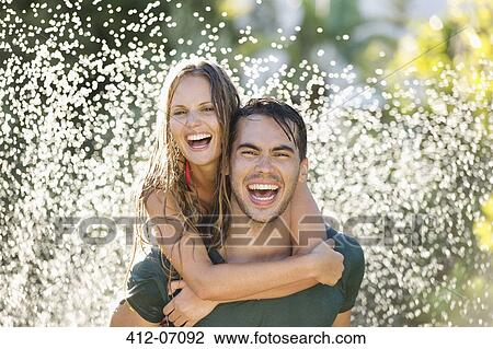 Couple playing in sprinkler in backyard View Large Photo Image Stock Image - Couple playing in sprinkler in backyard. Fotosearch
