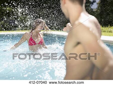 Stock Image - Couple playing in swimming pool. Fotosearch
