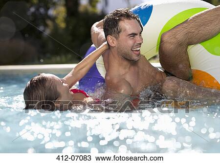 Stock Image - Couple playing in swimming pool. Fotosearch