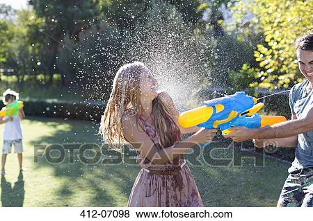 Couple playing with water guns in backyard View Large Photo Image Stock Photo - Couple playing with water guns in backyard. Fotosearch
