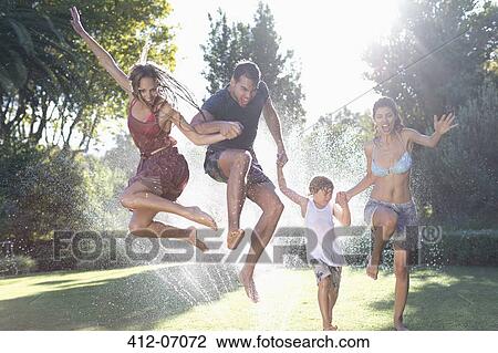 Family jumping in sprinkler View Large Photo Image Stock Image - Family jumping in sprinkler. Fotosearch