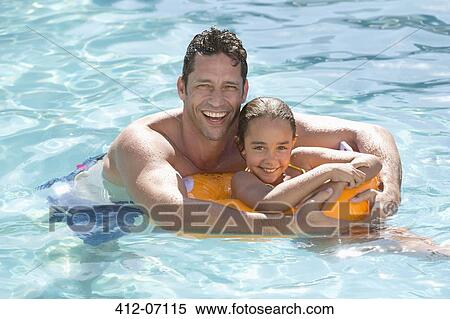 Stock Photography - Father and daughter relaxing in swimming pool. Fotosearch