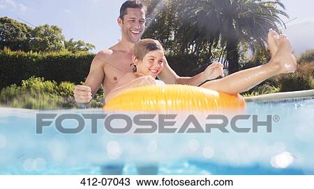 Stock Image - Father and son playing in swimming pool. Fotosearch