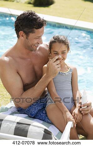 Father applying sunscreen to daughter's nose by swimming pool View Large Photo Image Stock Photo - Father applying sunscreen to daughter's nose by swimming pool. Fotosearch