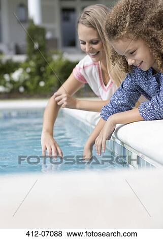 Mother and daughter dipping fingers in swimming pool View Large Photo Image Stock Photo - Mother and daughter dipping fingers in swimming pool. Fotosearch