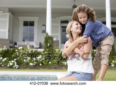 Stock Photograph - Mother and daughter hugging by swimming pool. Fotosearch