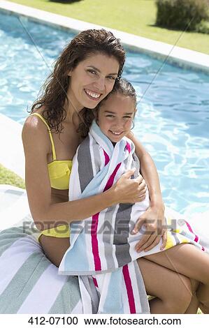 Stock Image - Mother and daughter relaxing by swimming pool. Fotosearch