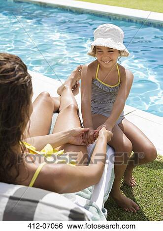 Mother and daughter sitting by swimming pool View Large Photo Image Stock Photograph - Mother and daughter sitting by swimming pool. Fotosearch