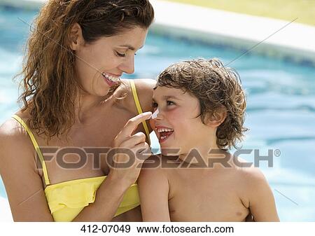 Stock Photo - Mother applying sunscreen to son's face. Fotosearch