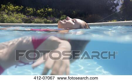 Stock Photo - Woman floating in swimming pool. Fotosearch
