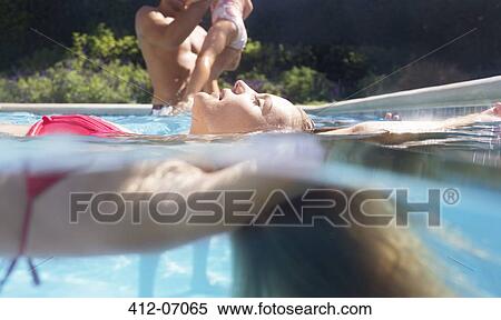 Stock Photography - Woman floating in swimming pool. Fotosearch