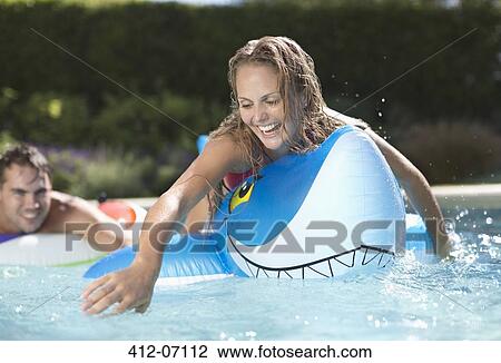 Woman playing on inflatable toy in swimming pool View Large Photo Image Stock Image - Woman playing on inflatable toy in swimming pool. Fotosearch