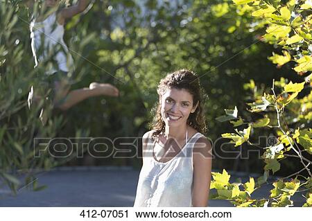 Stock Image - Woman standing by children on trampoline. Fotosearch