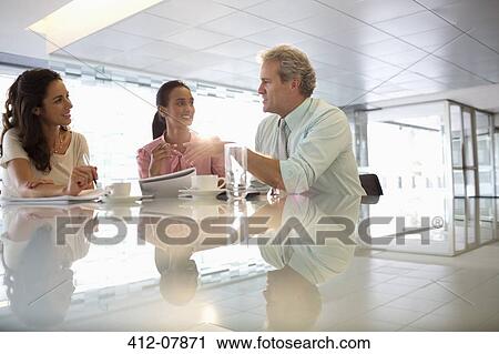 Stock Image - Business people talking in lobby. Fotosearch