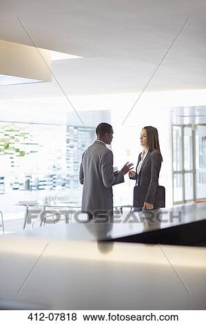 Stock Photo - Businessman and businesswoman talking in lobby. Fotosearch