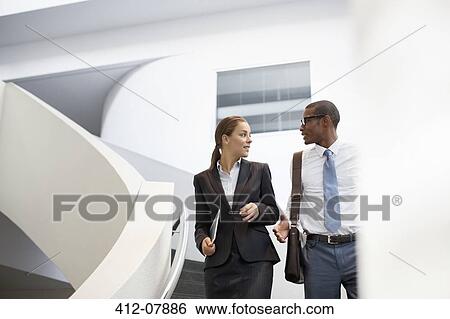 Stock Photograph - Businessman and businesswoman talking on modern staircase. Fotosearch